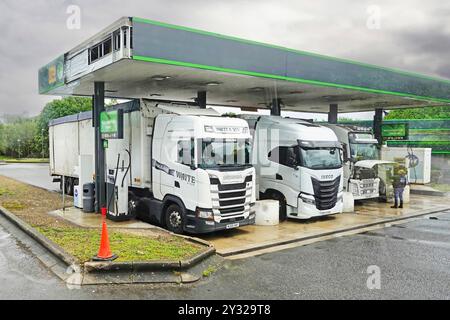 Haulage businesses lorries & trucks refuelling at M4 Membury motorway services one driver checking under raised bonnet Lambourn Berkshire England UK Stock Photo