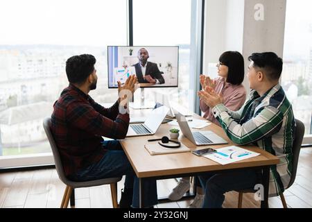 Team video conference meeting with applause in modern office Stock Photo