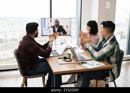 Business team in conference call with colleague clapping and celebrating success Stock Photo