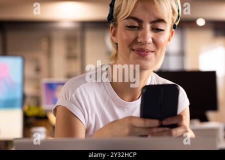 Using smartphone, woman smiling and working in creative writing business office Stock Photo