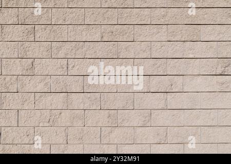 Close-up of a textured stone wall with uniform rectangular blocks, evenly arranged in rows. Backgrounds and textures Stock Photo