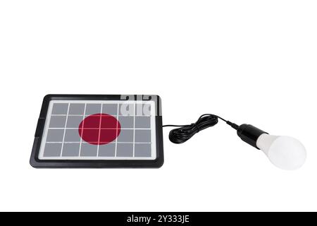 Portable solar panel in the shape of Japan flag connected to light bulb isolated on white background (close-up) Stock Photo