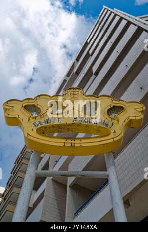 A weathered yellow sign shaped like a crown stands tall, reading 'Centro Comercial' in faded letters Stock Photo