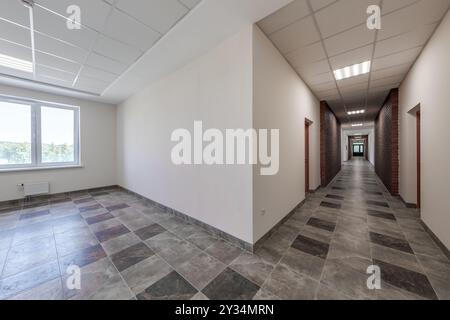 empty long corridor with red brick walls and doors in interior of modern apartments or office Stock Photo