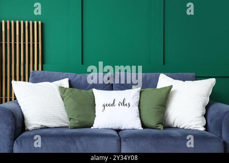 Comfortable sofa with different pillows near green wall in living room Stock Photo