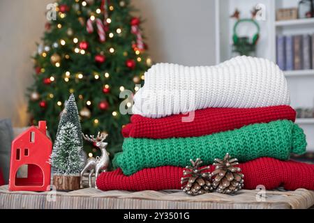 Stack of winter clothes with Christmas decorations on wicker table at home Stock Photo