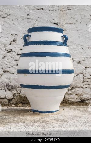 Old blue and white amphora lay on the ground in front of a white wall on the island of Crete Stock Photo