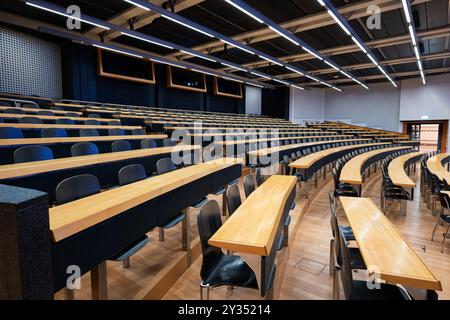Empty college or university classroom or lecture hall. Wooden desks and benches, no people. Stock Photo