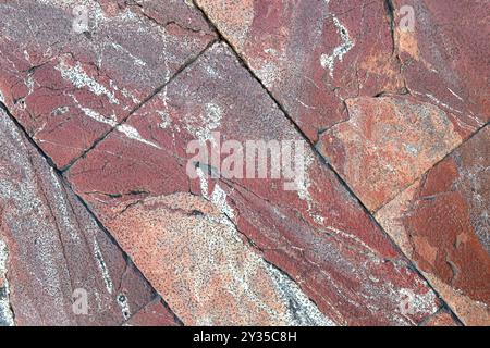 Abstract intricate textures and colors of a red and brown floor stone surface, highlighting unique patterns. Rough background Stock Photo