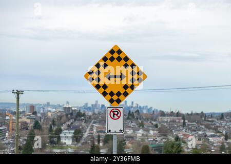 A road sign showing left and right directions with a 'No Parking' symbol, overlooking a city skyline in the background. Stock Photo