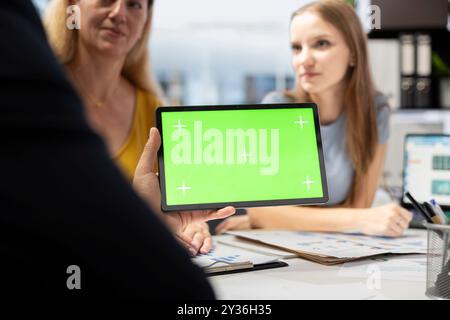 Financial adviser assisting clients in setting up investment accounts with green screen tablet, conducting audit. Consultant uses financial planning software on mockup device to help family, close up Stock Photo