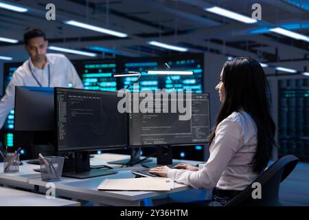 Software developer using computer, optimizing data center performance. Woman coding on PC, troubleshooting mainframes, ensuring optimal performance and minimizing downtime Stock Photo