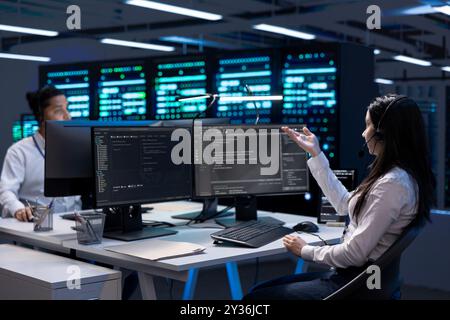 Data center workers in remote call, providing customer support, troubleshooting damages. Coworkers in server hub carrying out operational interventions requested by clients, using microphone Stock Photo
