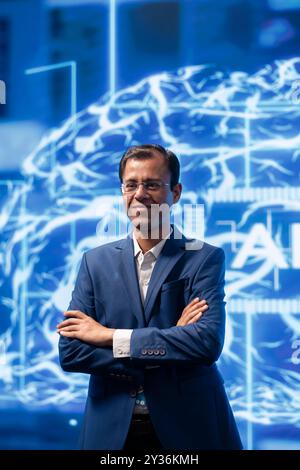 Portrait of smiling technician running artificial intelligence programming scripts in modern lab. Joyful admin working in IT department tasked with AI applications development Stock Photo