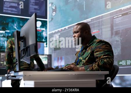 Military expert in an advanced operations center oversees satellite intelligence, managing surveillance systems on computer. Interpreting data to ensure national defense and strategic decisions. Stock Photo