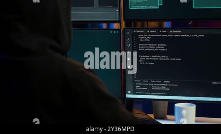 Dangerous man hacking, stealing credit card numbers and infiltrating banking systems, handheld camera shot. Close up of hacker running code in apartment on PC monitors, camera A Stock Photo