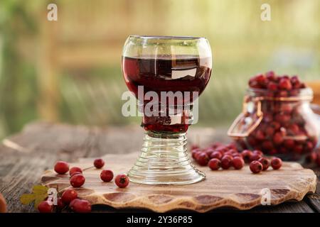 Medicinal wine made of fresh hawthorn berries in a cup made of so called forest glass containing air bubbles Stock Photo