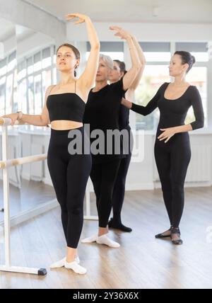 Women mastering third position under guidance of ballet teacher Stock Photo