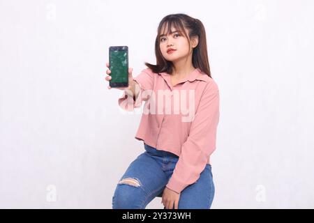 Beautiful happy asian woman in her 20s wearing casual shirt holding mobile phone looking at camera on white color background studio portrait for banne Stock Photo