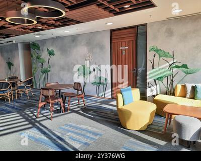 Modern office cafetaria with decorative plant on the wall, warm light with empty chair and table. Office Pantry. Stock Photo