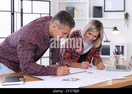 Architects making engineering drawing at wooden table in office Stock Photo