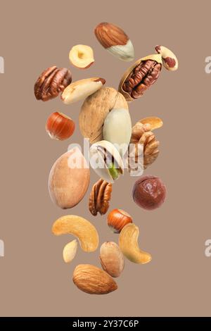 Pecan and other nuts in air on dark beige background Stock Photo