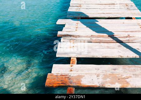 Old wooden pier with broken planks. Wooden dock overlooking calm water Stock Photo