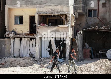 Tulakrm, Palestine. 12th Sep, 2024. Palestinians walk past destroyed buildings following an Israeli army raid in Tulkarm and its camps in the north of the occupied-West Bank. Israeli Defence Minister Yoav Gallant said on September 11 that the military should use its 'full strength' to strike at Palestinian militants in the occupied West Bank, where a sweeping military operation has killed dozens. Credit: SOPA Images Limited/Alamy Live News Stock Photo