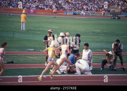 Aug 20, 1984; Los Angeles, CA, USA; At the 1984 Olympic finals, during the 3,000 meter run, MARY DECKER got tangled up with Zola Budd, a South African native who was running for Great Britain. Decker tripped, fell onto the field, and injured her hip.Picture: Medics tend to DECKER as other runners pass. Credit: Arthur Grace/ZUMAPRESS.com/Alamy Live News Stock Photo