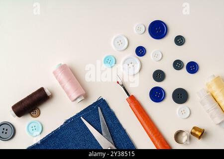 Sewing supplies and denim fabric arranged on a workspace for clothing alterations in a bright setting Stock Photo