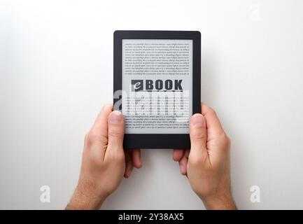Hands holding an ebook with text on screen on white isolated table. Top view Stock Photo
