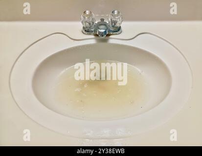 Bathroom sink blocked drain plumbing problems dirty water vanity countertop. Stock Photo