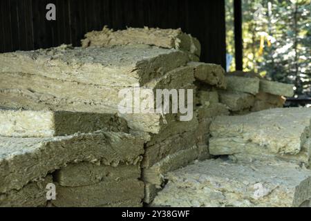 Bales of insulation material stored in a wooden barn during daylight hours Stock Photo