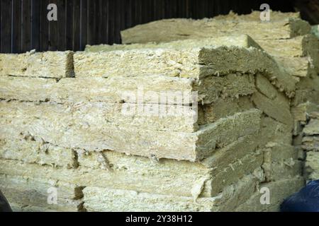 Bales of insulation material stored in a wooden barn during daylight hours Stock Photo