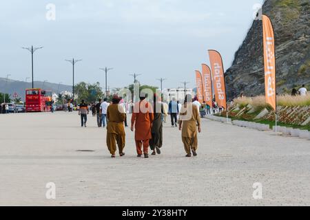 Back view of group of 4 young poor middle eastern migrant men wearing colorful traditional casual cloth walking on streets for Eid Al Fitr vacation Stock Photo