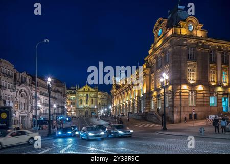 Evening scene of Rua das Flores street featuring Sao Bento railway station and Sao Antonio dos Congregados church in Porto, Portugal, with illuminated Stock Photo