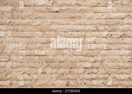 Textured beige stone wall with rectangular blocks in a modern architectural setting Stock Photo