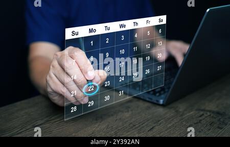 Planning and time management concept. A man manages his time using calendar on virtual screen interface, using his stylus to highlight the date to rem Stock Photo
