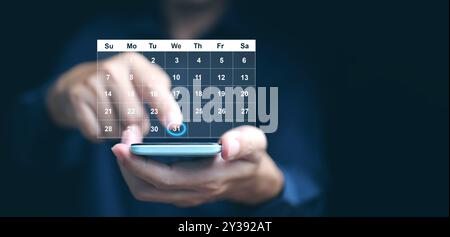 Planning and time management concept. A man manages his time using a virtual screen calendar interface on his smartphone Stock Photo