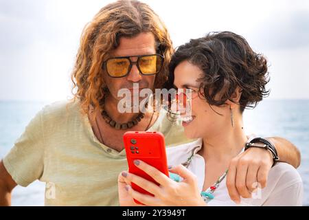 Smiling couple on the beach browsing smartphone apps. Stock Photo