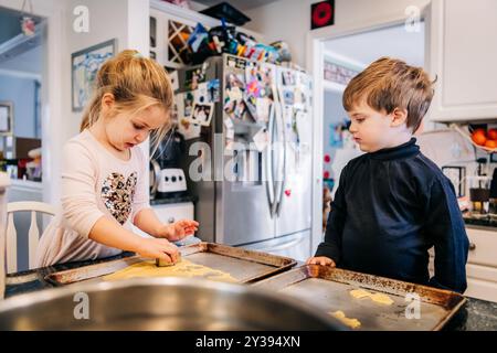 Two children working together on cookies in the kitchen Stock Photo