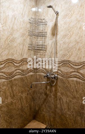 shower stand in rustic guest house lined with brown ceramic tiles Stock Photo