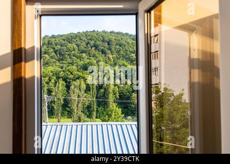 view of roof and green mountain through open window on sunny summer day in Dilijan city, Armenia Stock Photo