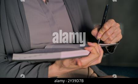 Close up of female psychologist taking notes in notebook while listening to patient, doing psychological test. Therapist provides psychotherapy during counseling session. Psychology and mental health. Stock Photo