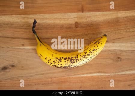 Single overripe banana on wooden background, Top view, close up shot, no people. Stock Photo