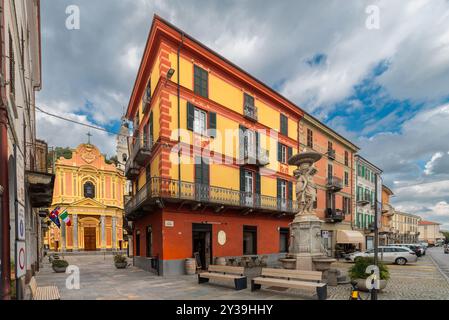 Caraglio, Italy - September 06, 2024: view of Via Roma with old decorated buildings and the fountain of the three graces, in the background the parish Stock Photo