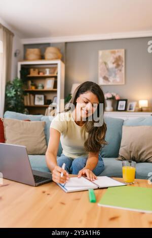 Happy woman working at home and taking notes Stock Photo