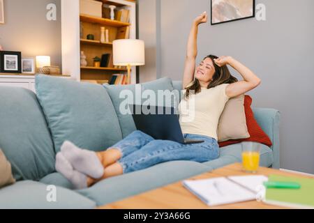 Woman stretching and relaxing on the couch after a long work session Stock Photo