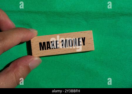 Make money message written on wooden block with green background. Conceptual make money symbol. Copy space. Stock Photo