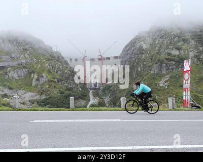 Anton Geisser 12.09.2024 Kanton Bern Schweiz. Kraftwerke Oberhasli Staumauer .Neubau Spittallam. Bild die Ersatzstaumauer im Nebel .Radfahrer auf dem Weg zum Grimsel. *** Anton Geisser 12 09 2024 Canton of Berne Switzerland Oberhasli power stations New Spittallam dam Image of the replacement dam in the fog Cyclists on the way to Grimsel Stock Photo